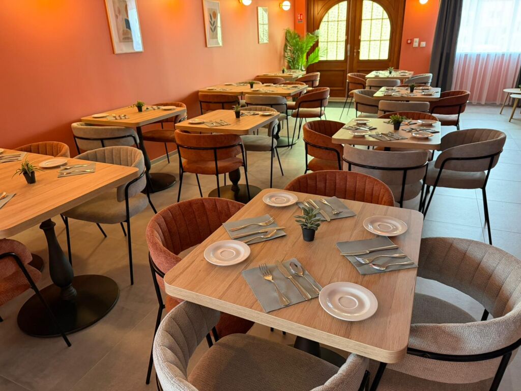Salle du petit-déjeuner — murs corail, chaises en velours, porte cintrée